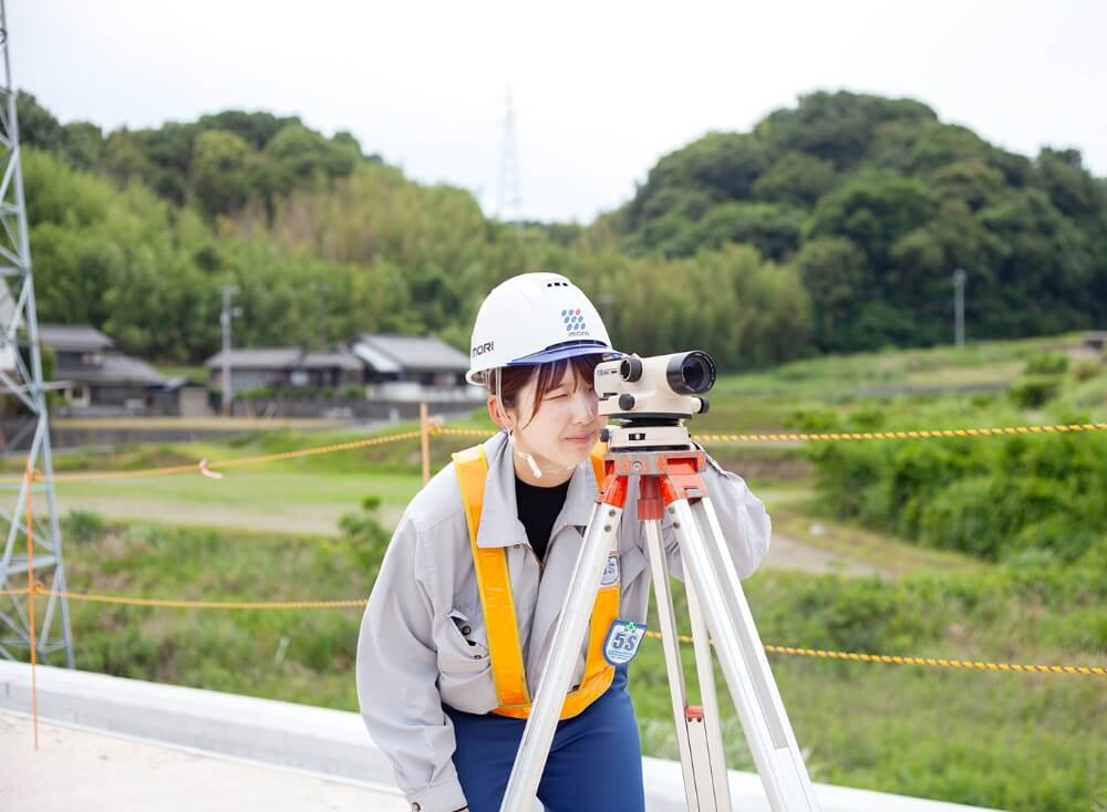 測量機をのぞき込んでいる女性従業員